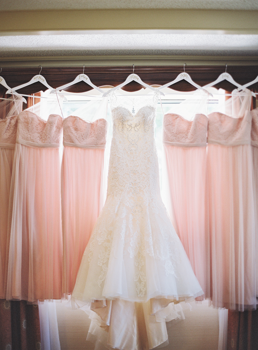 photo of brides dress with bridesmaids dresses hanging on window ledge