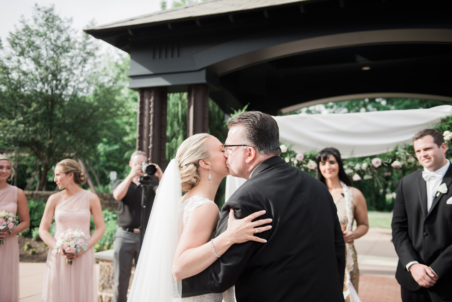bride giving her father a kiss at the end of the aisle