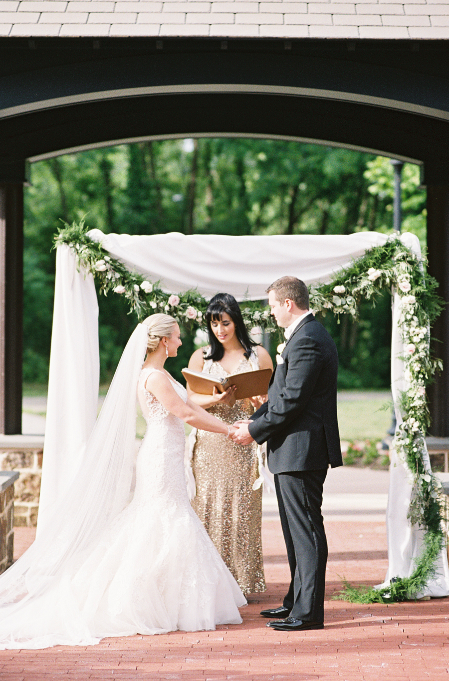 film image of bride, groom and officiant in the middle of the aisle