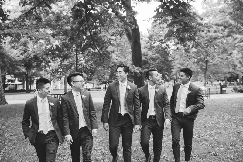 black and white image of groom walking with his groomsmen